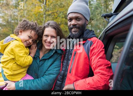 Portrait heureuse famille multiethnique debout à l'extérieur de la voiture Banque D'Images