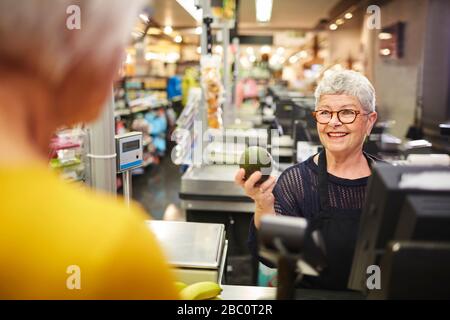 Une femme souriante qui aide le client à payer les courses Banque D'Images
