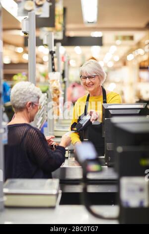 Caissier senior pour aider le client au moment de la commande au supermarché Banque D'Images