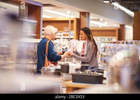 Une femme qui aide une femme âgée à faire des achats dans un magasin de biens domestiques Banque D'Images