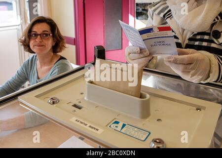 VÉRIFICATION DE LA CARTE DE L'ÉLECTEUR BFORE LE VOTE, LORS DU PREMIER TOUR DES ÉLECTIONS MUNICIPALES, TOUT EN RESPECTANT LES MESURES SANITAIRES PRISES À LA LUMIÈRE DE LA PANDÉMIE DE CORONAVIRUS, POSTE DE VOTE À RUGLES, NORMANDIE, FRANCE Banque D'Images