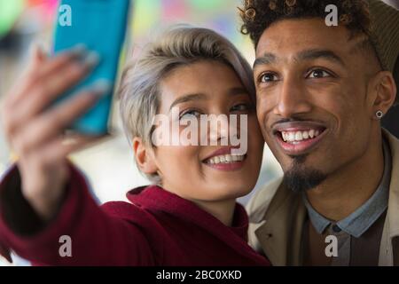 Smiling young couple with camera phone selfies Banque D'Images