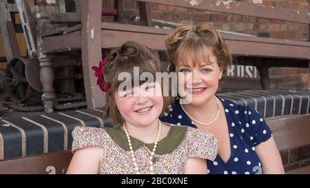 Mère et fille souriantes ensemble, femme et fille de la mode des années 1940, événement d'été de la guerre du chemin de fer de Severn Valley, gare de Kidderminster, Royaume-Uni. Banque D'Images