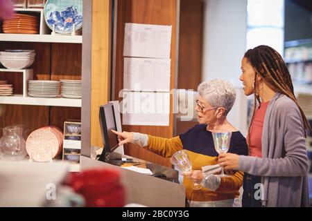 Une employée senior aide le client à utiliser la verrerie Banque D'Images