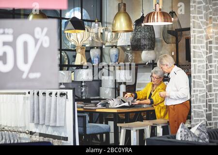 Les femmes les plus âgées font du shopping, en regardant les nuances de tissu dans la boutique de décoration à domicile Banque D'Images