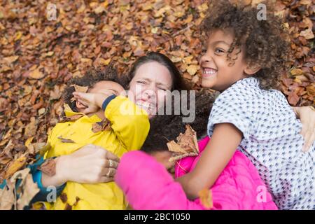 Portrait bonne mère et enfants jouant en automne feuilles Banque D'Images