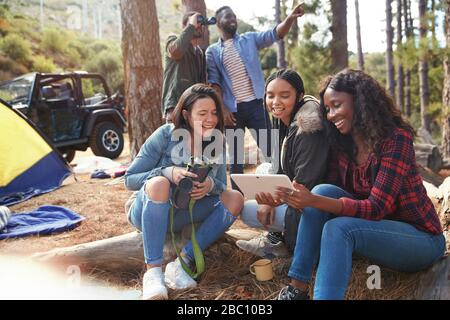 Souriant jeunes femmes amis utilisant une tablette numérique au camping Banque D'Images