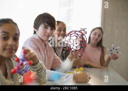 Portrait des étudiants confiants qui détiennent des structures moléculaires en salle de classe de laboratoire Banque D'Images