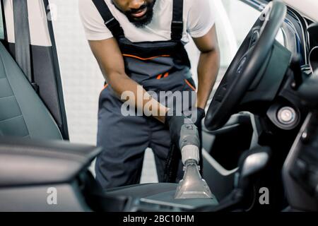 Détails de l'aspirateur de voiture. Travailleur masculin africain utilisant un aspirateur humide pour l'intérieur sale de la voiture. Nettoyage auto car du Banque D'Images