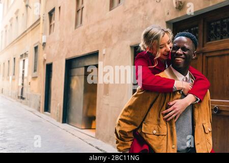 Un jeune homme heureux transportant une petite amie se portant dans une ruelle de la ville de Florence, en Italie Banque D'Images