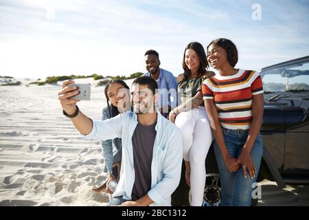 De jeunes amis avec un appareil photo téléphone prenant selfie sur la plage Banque D'Images