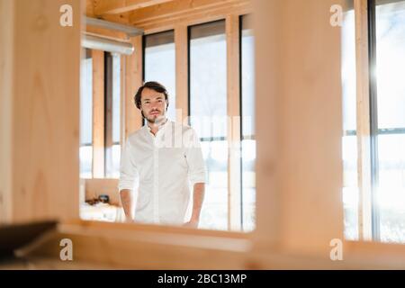 Homme d'affaires debout à la fenêtre dans un bureau en bois ouvert Banque D'Images