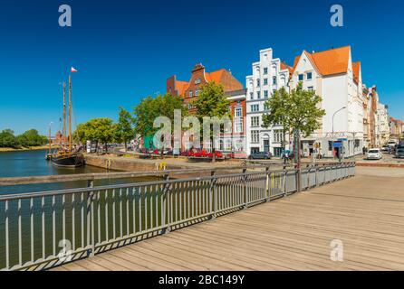 Lubeck (Lübeck) - juillet 2018, Allemagne: Paysage urbain de la vieille ville européenne avec bâtiments historiques, bateau en bois, et pont à travers la rivière Trave Banque D'Images