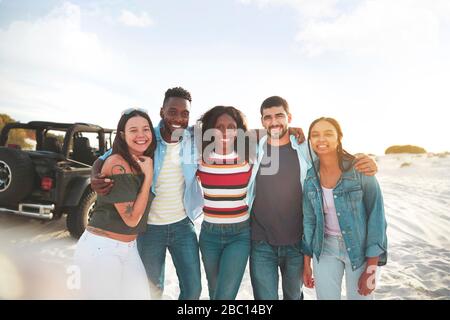 Portrait souriant de jeunes amis sur la plage ensoleillée Banque D'Images