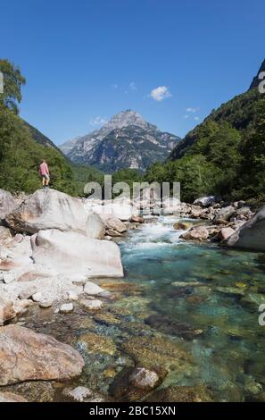 Homme debout sur le rocher de la rivière Verzasca, Verzasca Valley, Tessin, Suisse Banque D'Images