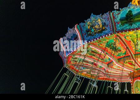 Allemagne, Bavière, Munich, carrousel à chaînes qui brille contre le ciel nocturne Banque D'Images