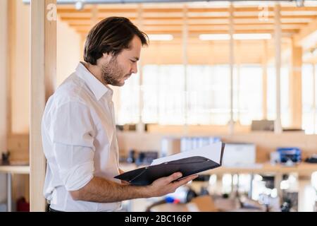 Bbusinessman regardant le dossier dans le bureau en bois ouvert Banque D'Images