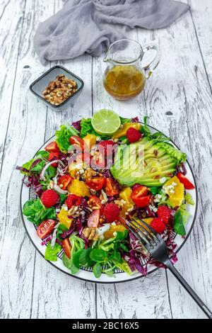 Assiette de salade mélangée colorée avec du fromage feta, de la betterave commune, des noix, des pignons, des framboises, des oranges et de la salade de maïs Banque D'Images