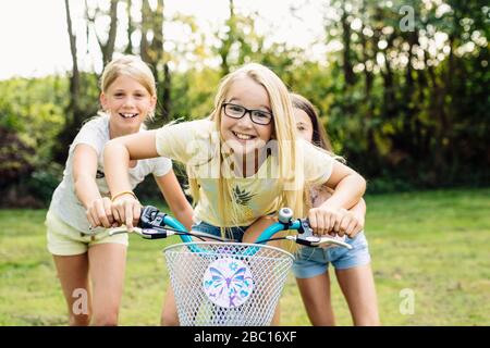 Bonnes filles à vélo dans le jardin Banque D'Images