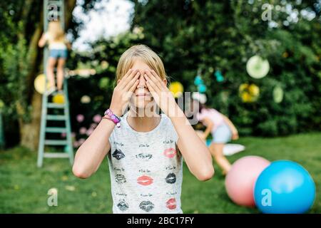 Les filles qui jouent se cachent et cherchent à faire une fête d'anniversaire à l'extérieur Banque D'Images