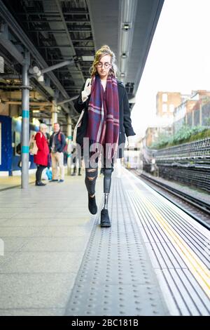 Jeune femme avec prothèse de jambe marchant à la station platfom Banque D'Images