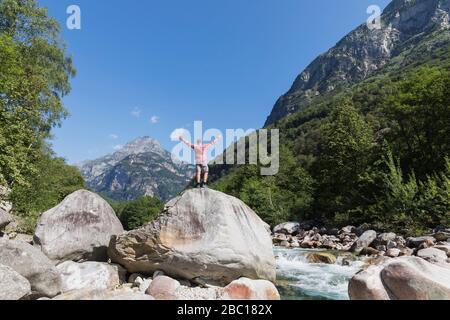 Homme debout sur le rocher de la rivière Verzasca, Verzasca Valley, Tessin, Suisse Banque D'Images