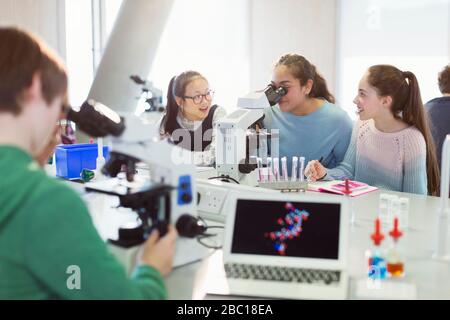 Jeunes filles au microscope, réalisation d'expériences scientifiques en salle de classe de laboratoire Banque D'Images