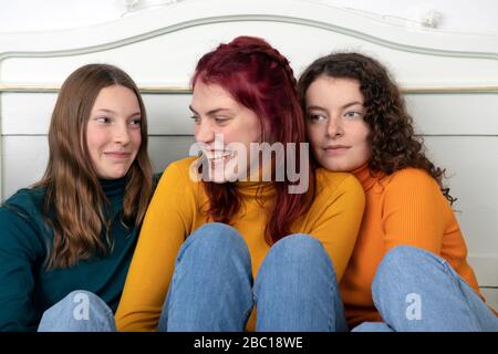 Portrait de trois sœurs heureuses assises ensemble sur le lit Banque D'Images