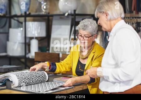 Femmes âgées regardant les nuances de tissu dans la boutique de décoration à la maison Banque D'Images