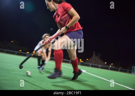 Les jeunes joueurs de hockey sur gazon qui jouent pour le ballon, jouent sur le terrain la nuit Banque D'Images