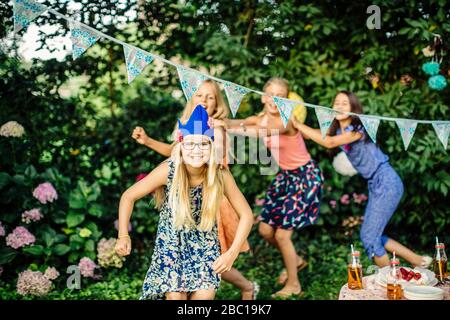 Les filles heureuses qui font une ligne de conga sur une fête d'anniversaire en plein air Banque D'Images