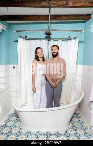 Jeune couple debout dans la baignoire, rire Banque D'Images