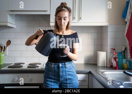 Jeune femme préparant un café instantané dans la cuisine à la maison Banque D'Images