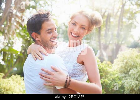 Portrait souriant jeune couple embrassant dans le parc Banque D'Images