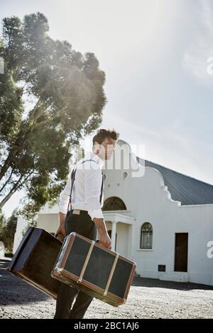 Homme dans des vêtements à l'ancienne avec des valises dans la campagne Banque D'Images