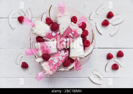 Des poissettes maison de noix de coco et de framboises dans un bol en verre Banque D'Images