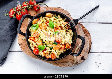 Une poêle de pâtes prêtes à manger avec tomates, crevettes, courgettes et basilic Banque D'Images