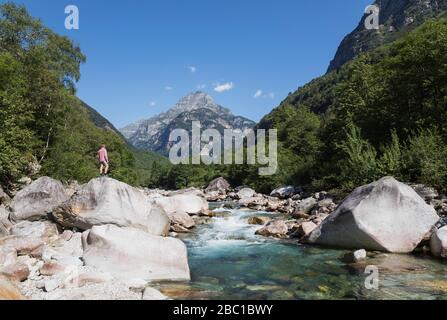 Homme debout sur le rocher de la rivière Verzasca, Verzasca Valley, Tessin, Suisse Banque D'Images