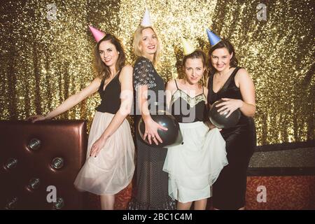 Portrait de quatre femmes heureuses portant des chapeaux de fête dans un club Banque D'Images