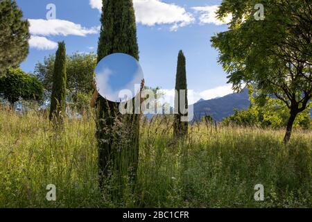 Femme cachant l'arbre de behing, tenant miroir, reflétant le ciel Banque D'Images