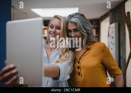 Portait de mère souriante et fille adulte tenant une tablette Banque D'Images