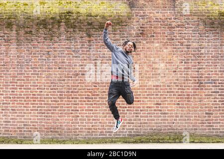 Jeune homme de sauter devant un mur de brique Banque D'Images
