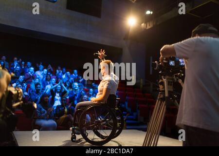 Haut-parleur féminin en fauteuil roulant sur scène pour se déplacer vers le public Banque D'Images