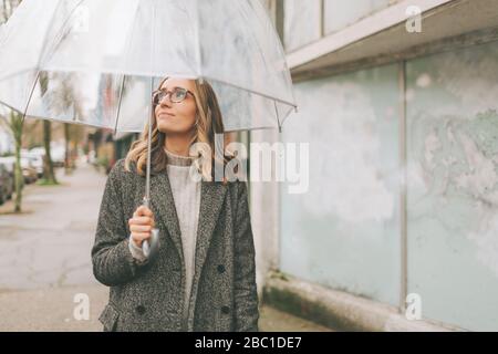 Blonde femme marchant dans la pluie avec un parapluie Banque D'Images