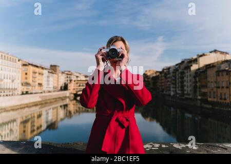 Jeune femme prenant une photo sur un pont au-dessus de la rivière Arno, Florence, Italie Banque D'Images