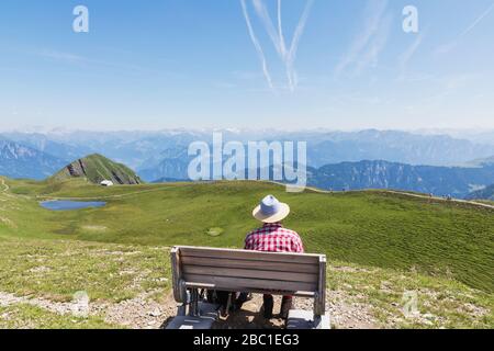 Suisse, St Gall Canton, Man reposant sur un banc, regardant sur les montagnes Banque D'Images