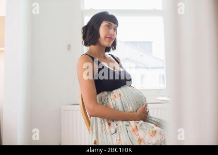 Femme enceinte réfléchie tenant l'estomac Banque D'Images