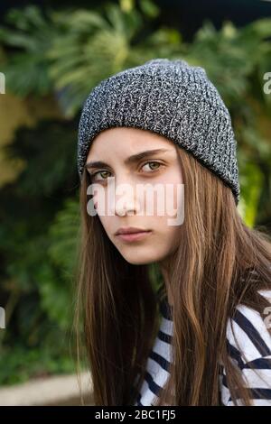 Portrait d'une jeune fille adolescente sérieuse avec de longs cheveux bruns portant un chapeau de laine grise Banque D'Images