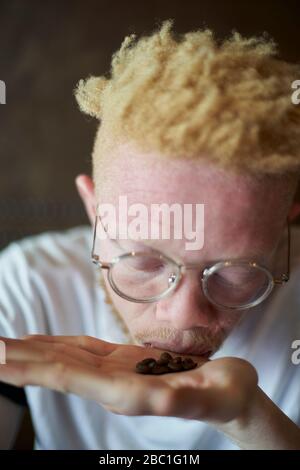 Albino homme dans une cafétéria qui sent les grains de café à la main Banque D'Images