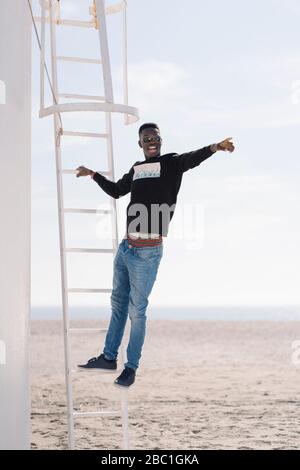 Un jeune homme élégant debout sur une échelle à la plage